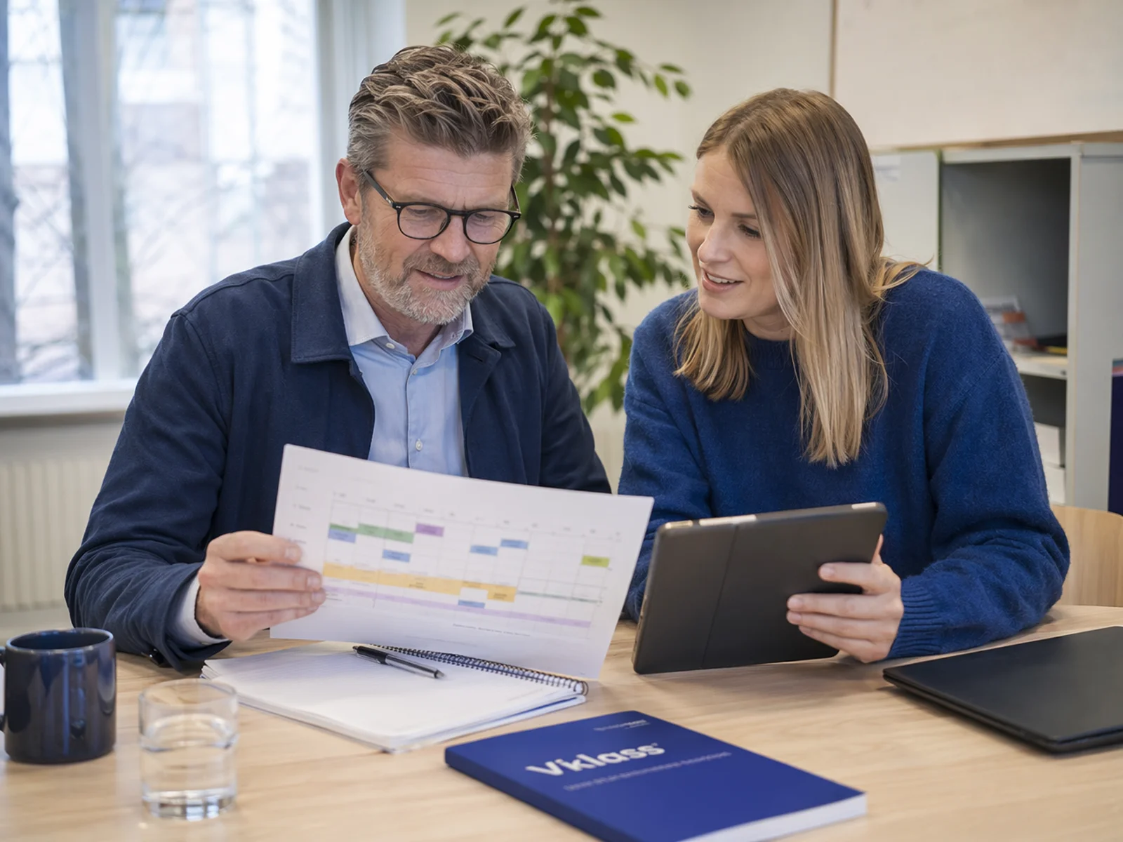 Rektor och biträdande rektor går igenom ett schema tillsammans vid ett mötesbord.